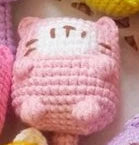 Pink crocheted cat plush toy on a soft pastel background
